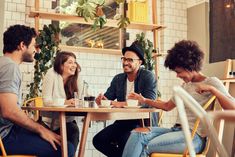 four people sitting at a table laughing and having conversation in a coffee shop or cafe