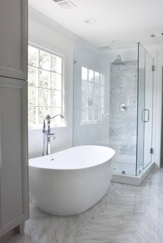 a large white bathtub sitting in the middle of a bathroom next to a walk in shower