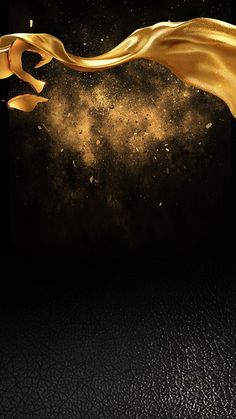 a gold cloth blowing in the wind on top of a black surface with stars and dust behind it