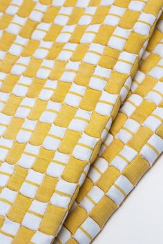 a yellow and white checkered fabric with small squares on the side, as if it were woven