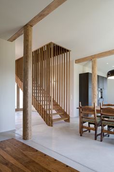 a dining room table and some chairs in front of a wooden stair case on the wall