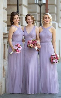 three bridesmaids in lavender colored dresses posing for the camera with their bouquets