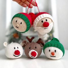 three knitted snowmen with hats and noses hanging from the strings on a white table