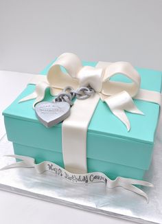 a cake that is shaped like a box with a heart on it and ribbon around the top