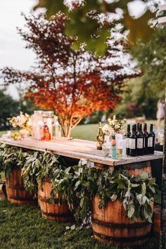 an outdoor bar is set up with wine bottles and candles on top of wooden barrels