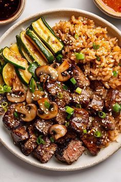 a white plate topped with meat and veggies covered in sauce next to rice