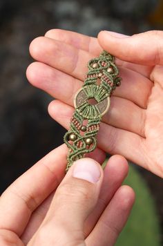 a hand holding a green beaded bracelet in it's right hand and another hand is holding the clasp