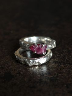 A unique ring with an uncut ruby complete with a sterling silver band. A unique ring with a unique stone - a raw ruby from Tanzania. The stone has an irregular shape and a dark pink color. Here and there you can see metallic inclusions of rutile, which makes this stone even more original. The approximate dimensions of the stone are 7 x 11 mm. The set includes a sterling silve ring with a texture matching the ring band, reminiscent of the raw texture of a rock. I designed the ring in such a way that its form emphasized the severity of the ruby. The thickness of the ring strip and the band varies between 3-5 mm.  I made the ring and wedding ring by hand from 925 silver using the sand casting technique.  This is a unique product, made in one piece in size 12 EU/6 US (internal diameter 16,5 mm Handmade Silver Ruby Ring For Wedding, Raw Ruby Engagement Rings, Unique Handmade Red Ruby Ring, Handmade Vintage Sterling Silver Ruby Ring, Luxury Handmade Silver Ruby Ring, Raw Sapphire Ring, Ruby Ring Set, Raw Texture, Raw Ruby