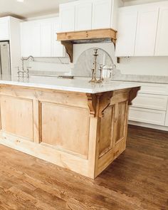 a large kitchen with white cabinets and wood flooring, an island in the middle