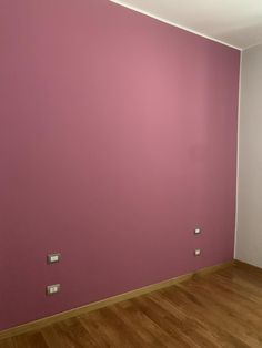 an empty room with pink walls and wood floors