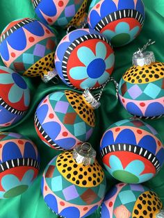 many colorful ornaments are arranged on a green cloth with polka dots and circles painted on them