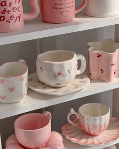 some pink and white cups and saucers are on the shelves in a room that is decorated with hearts