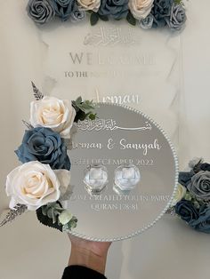 a person holding up a glass plaque with flowers on it that says welcome to the groom