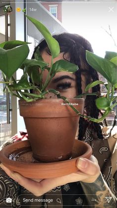 a woman holding a potted plant in front of her face