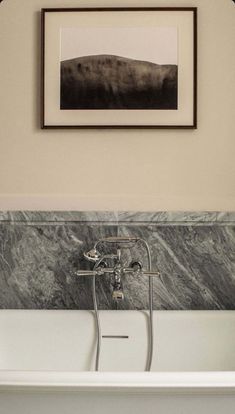 a white bath tub sitting under a framed picture