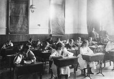 an old black and white photo of students at desks