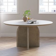 a white table with a plant on it in front of two windows and a wooden floor