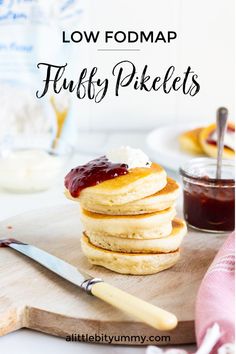 low fodmap fluffy pancakes with strawberry jam and butter on top, sitting on a cutting board