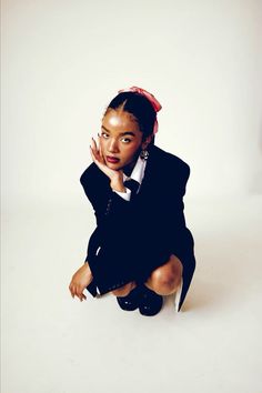 a woman sitting on the ground with her hand under her chin