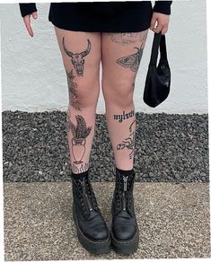 a woman with tattoos on her legs and leggings is holding a black bag