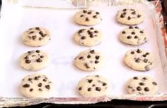 chocolate chip cookies sitting on top of a baking sheet covered in plastic wrapper, ready to go into the oven