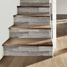 a wooden stair case with white walls and wood flooring on the bottom, next to an open door