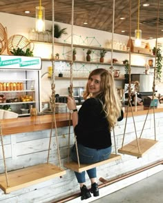 a woman sitting on a wooden swing in front of a counter