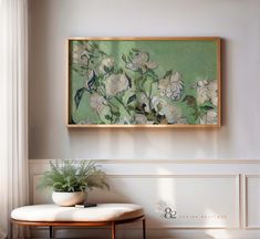 a painting hanging on the wall above a table with a potted plant next to it