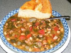 a blue and white bowl filled with soup next to a piece of bread on top of a table