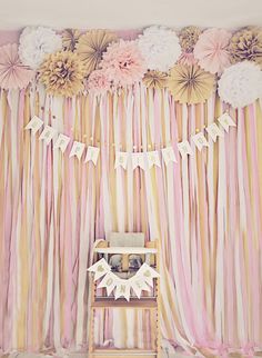 a baby's room decorated with pink and gold striped curtains, flowers and bunting