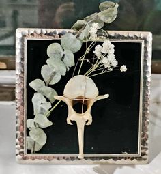 a vase with some flowers in it sitting on a table next to a framed photo