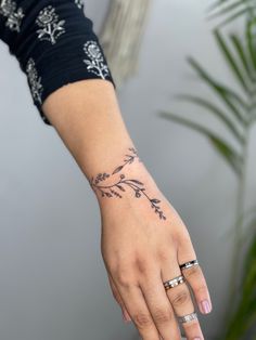 a woman's hand with a flower tattoo on her left wrist and two wedding bands