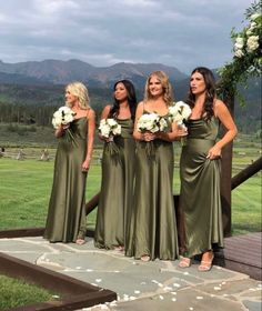 the bridesmaids are all dressed in olive green dresses with white flowers on their bouquets