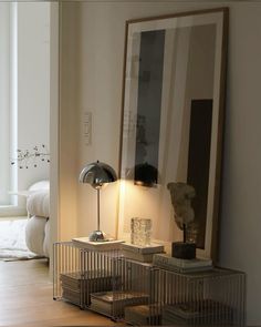 an animal cage sitting on top of a wooden floor next to a lamp and painting