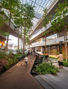 people are walking around in the atrium of a building with trees and plants on display