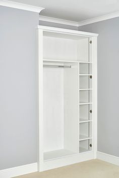 an empty white closet in a room with carpeted flooring and walls painted gray