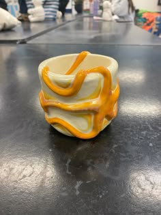 a yellow and white bowl sitting on top of a black table with people in the background