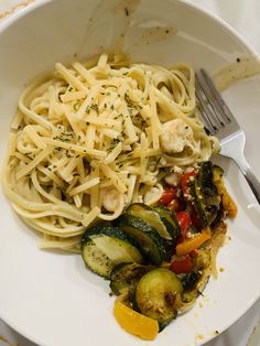 a white plate topped with pasta and veggies next to a knife and fork