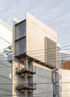 an apartment building with multiple balconies and plants on the top floor, in front of power lines