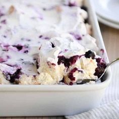 a close up of a casserole dish with blueberries and cream