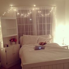 a laptop computer sitting on top of a bed in a room with white furniture and lights