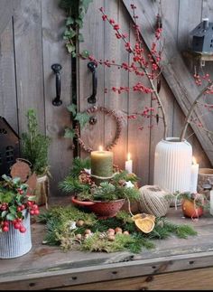 a table topped with lots of christmas decorations and candles next to a wall covered in wood planks