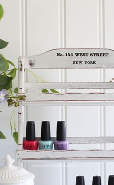 the nail polish bottles are lined up in front of an old white shelf with greenery