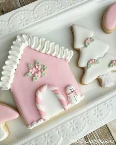 some decorated cookies are on a white platter with pink and white frosted icing