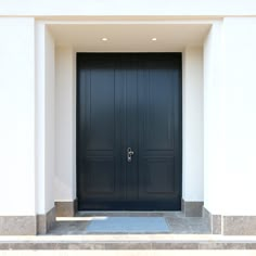 two black doors are open in front of a white building with steps leading up to it