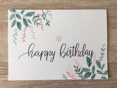 a card with the words happy birthday written in cursive writing and watercolor leaves