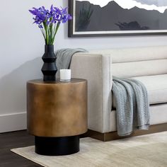 a living room with a couch, coffee table and flowers in the vase on the floor