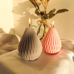 two vases with candles are sitting on a table next to a flower in a vase