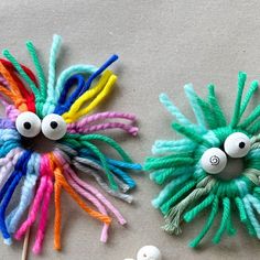 two colorful hair clips with googly eyes on top of each other, one has yarn wrapped around it