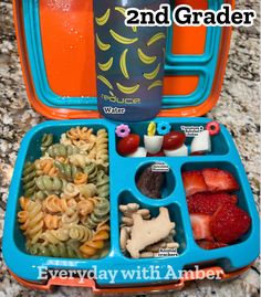 an orange and blue lunch box filled with pasta, fruit, and veggies